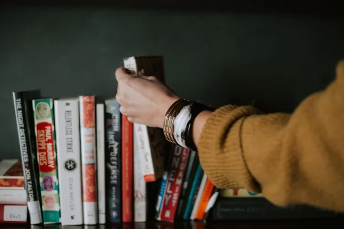 A hand reaches for a book on a shelf, showcasing creative inspiration and literature.