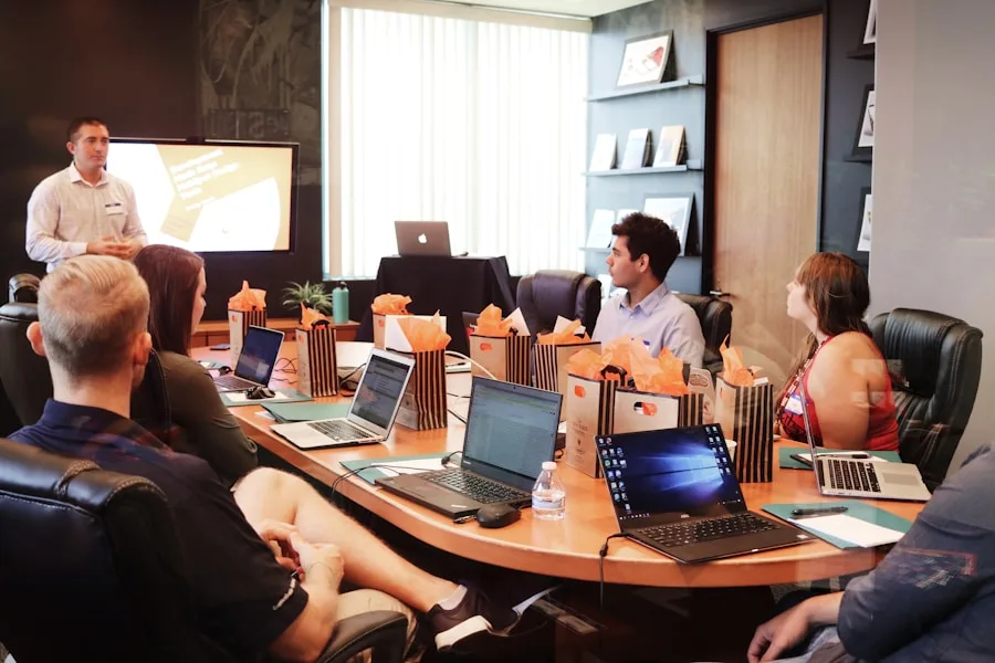 A business meeting is in progress around a conference table, discussing creative arts projects.