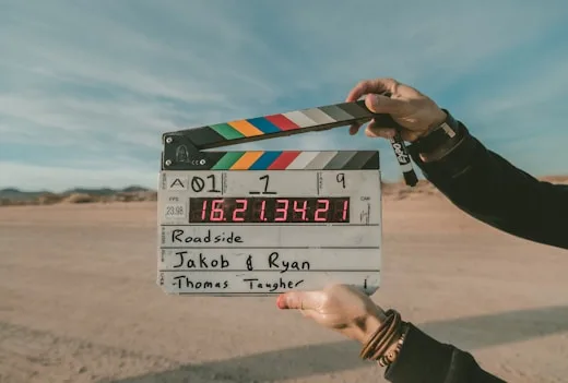 A clapperboard sits on a desert roadside during film production, showcasing creative arts services.