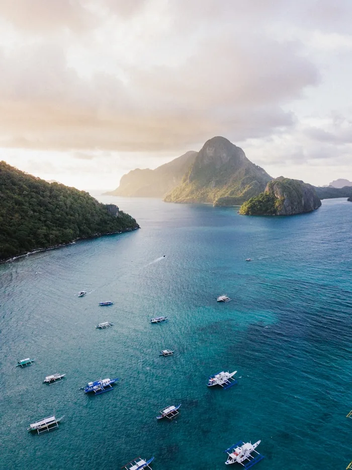 Boats rest on the turquoise waters near lush islands in El Nido, Palawan – a stunning showcase of travel destinations.