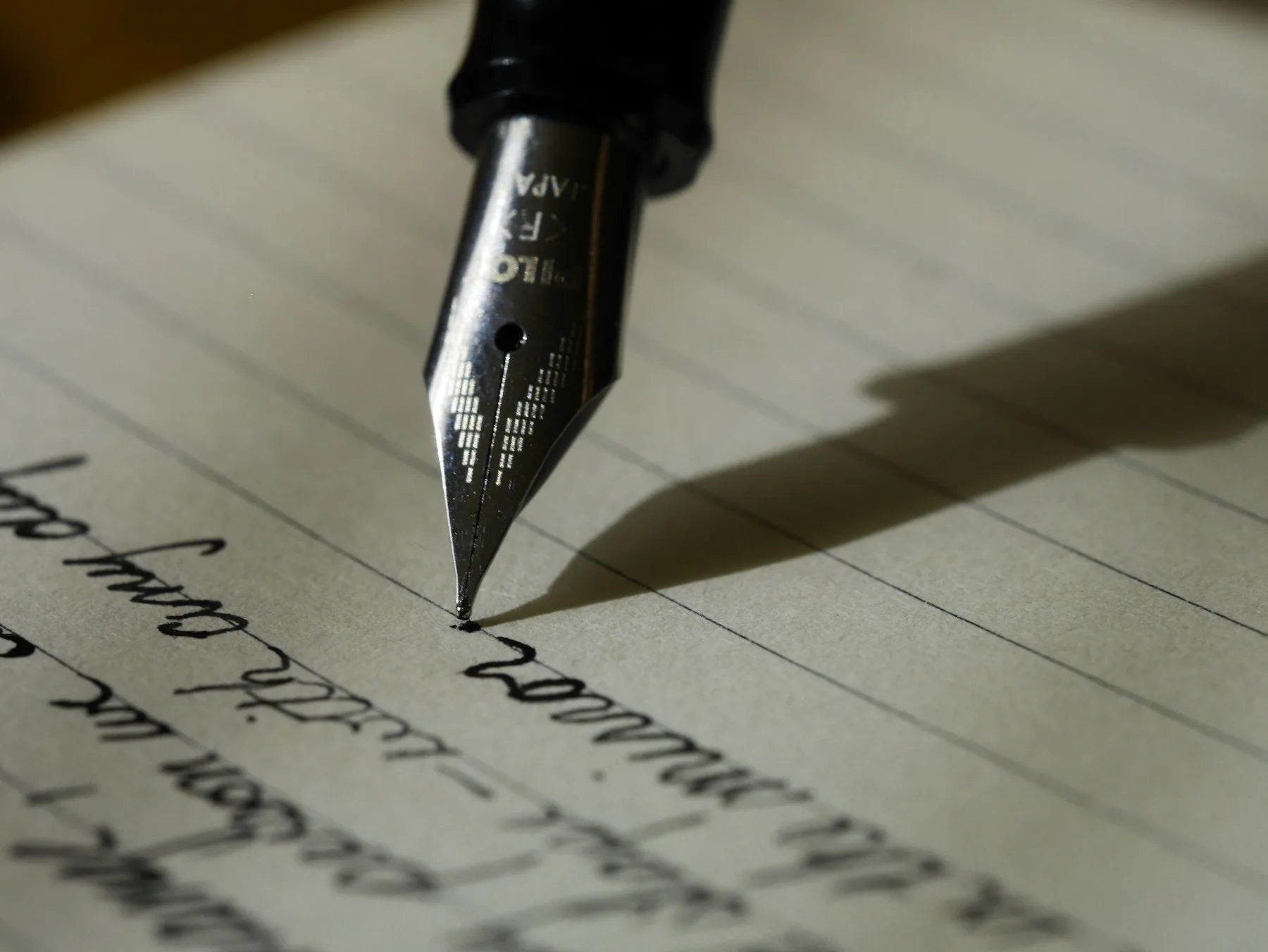 A fountain pen demonstrates creative writing, showcasing the art of calligraphy on lined paper.