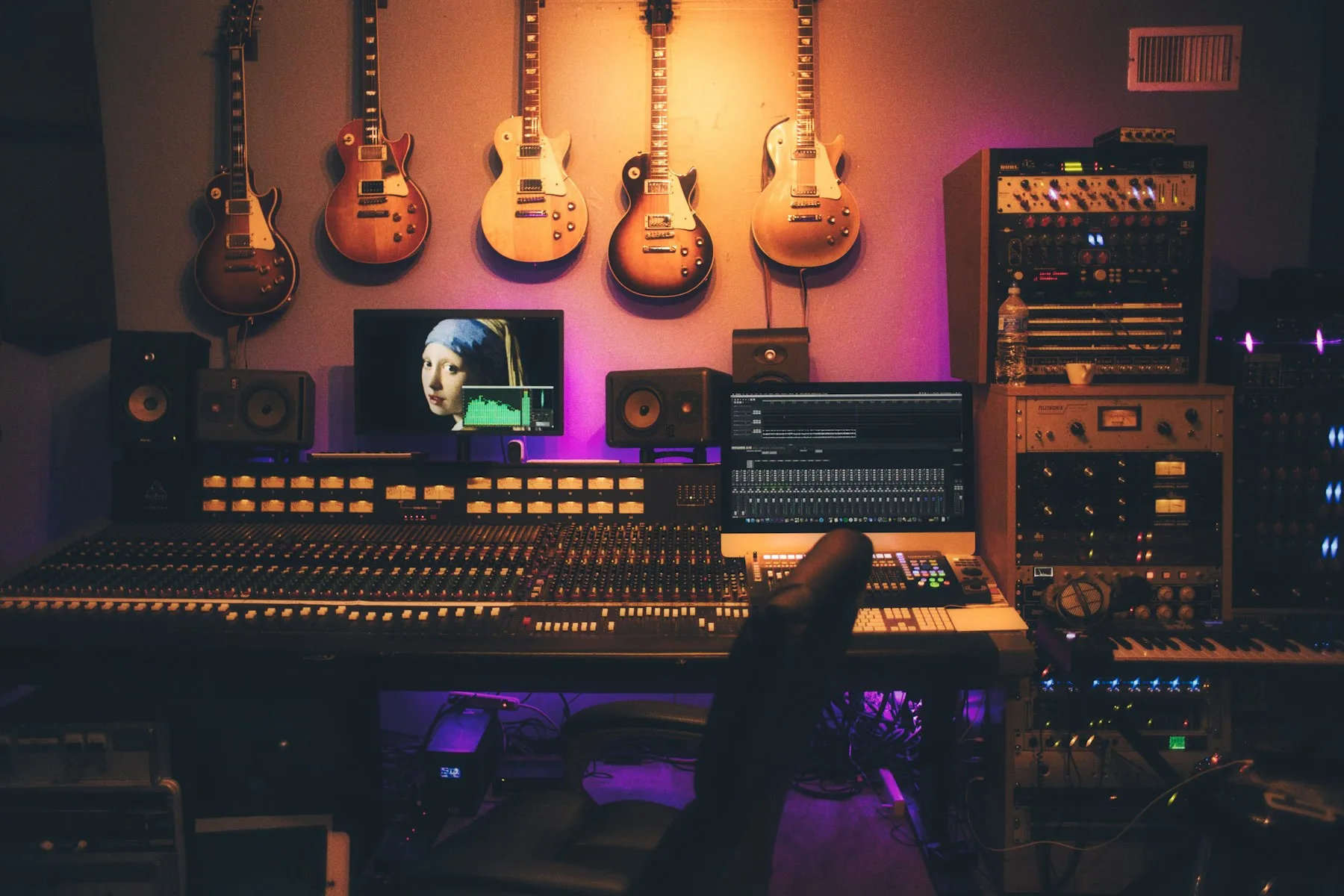 A recording studio with guitars and a mixing console showcases CAQA Creative's music production services.