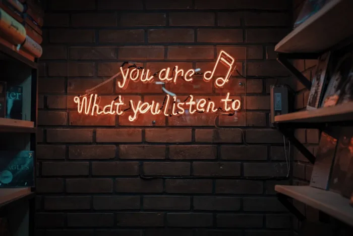 A brick wall features a neon sign displaying a musical quote alongside shelves of vinyl records, showcasing creative arts.