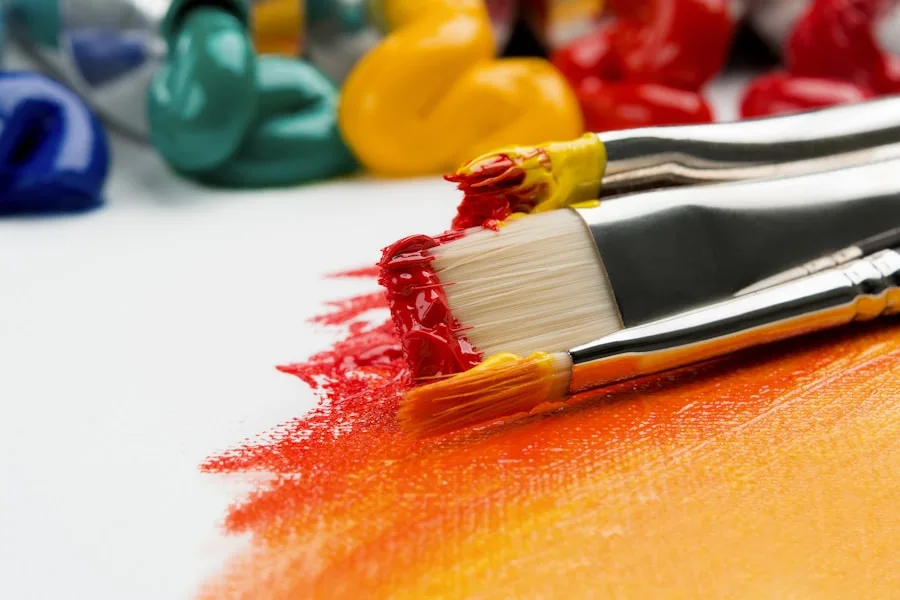 Paintbrushes and acrylic paints rest on a canvas, showcasing visual arts services offered by CAQA Creative.